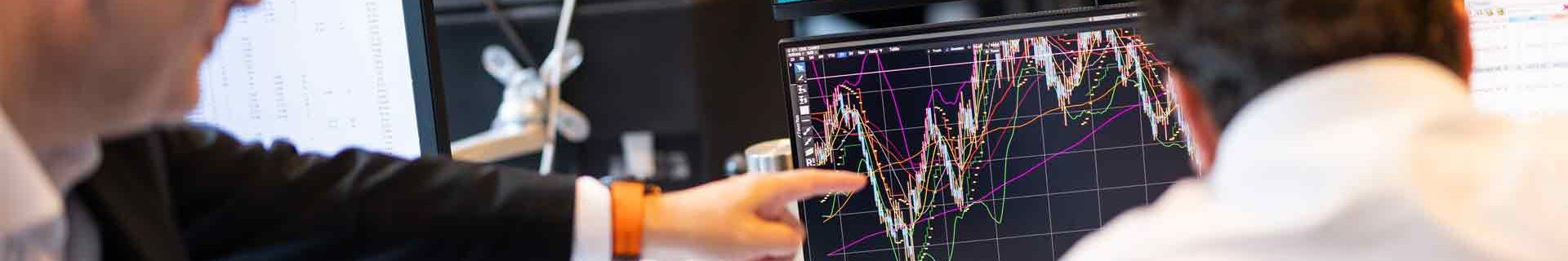 SF Two Individuals In An Office Setting Analyse Complex Financial Charts On Multiple Monitors 19